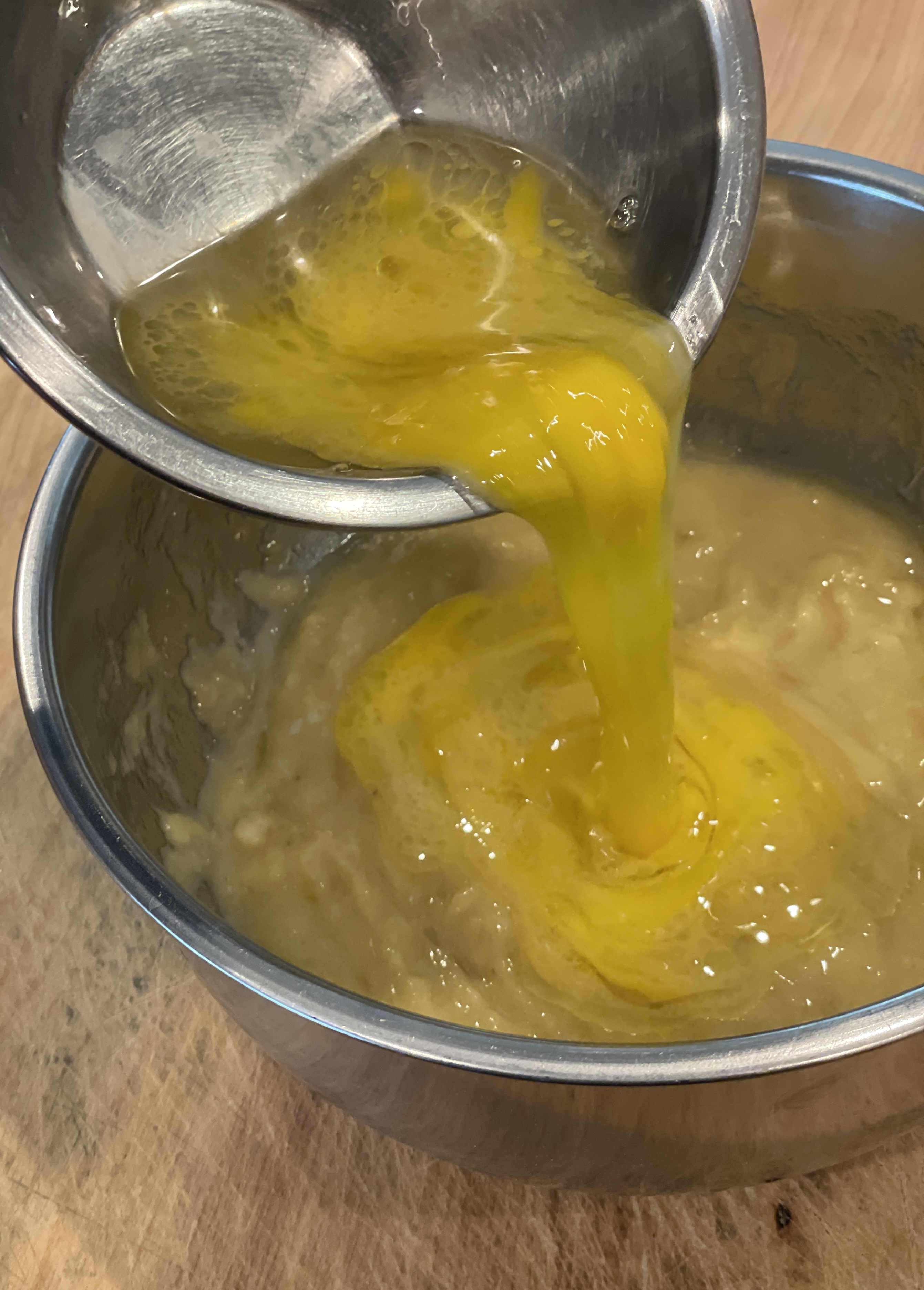 Egg and oil mixture being poured into mashed bananas
